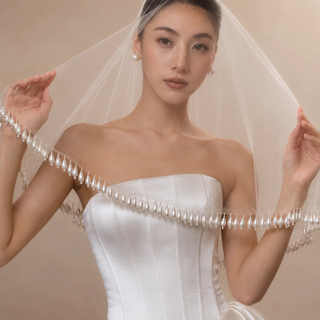 Woman wearing a white strapless wedding dress with a long veil against a beige background