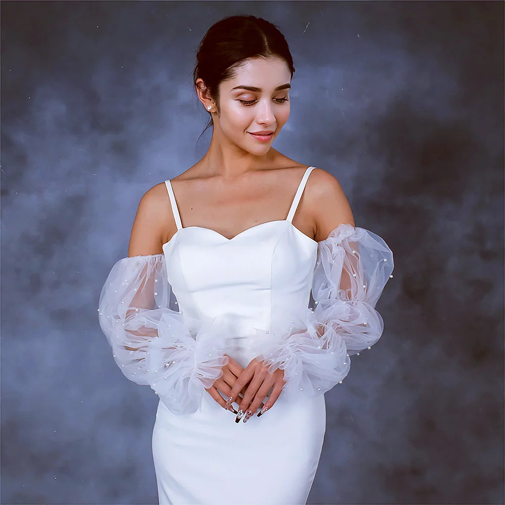 Woman wearing a white dress with sheer sleeves against a dark background