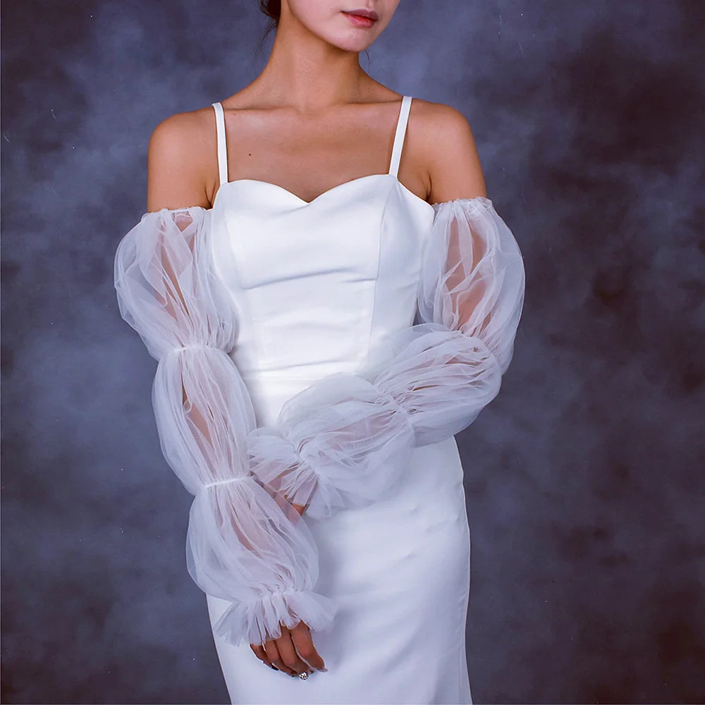 White wedding dress with sheer sleeves against a dark background
