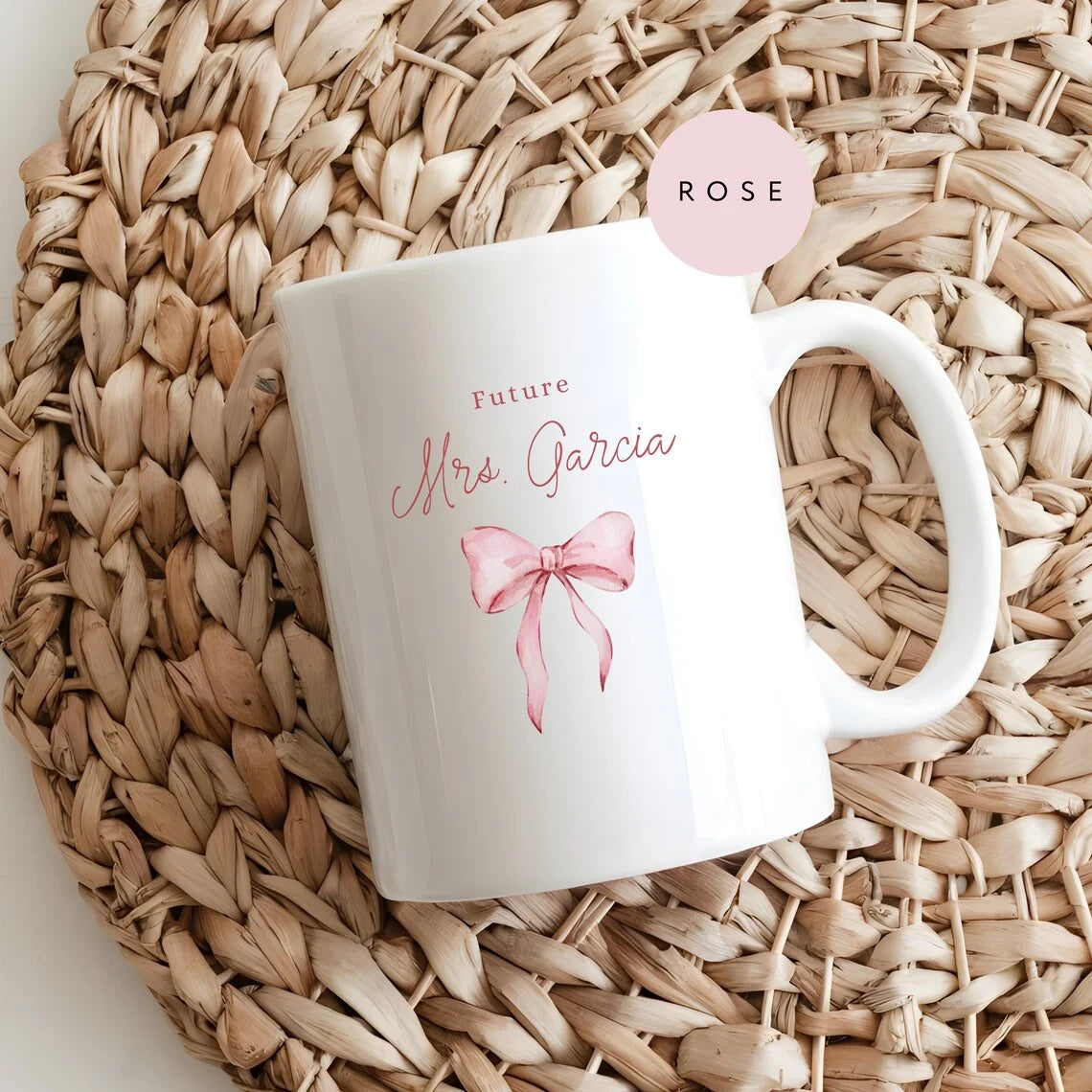White mug with 'Future Mrs Garcia' text and pink bow design on a woven mat