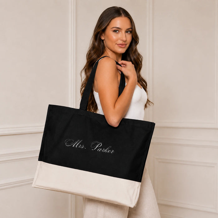 Woman holding a black tote bag with 'Mrs. Parker' text against a neutral background