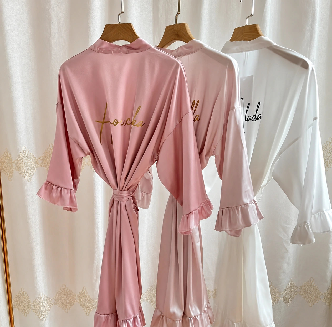 Pink satin pajama set with 'Foulee' branding on hangers against a white curtain background.