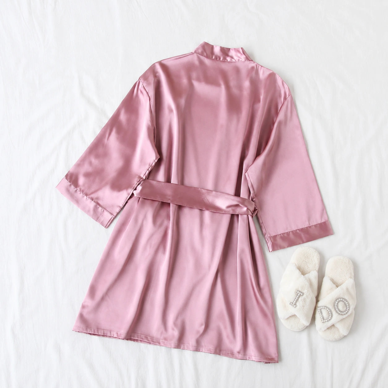 Pink satin robe with a belt and white slippers on a light background