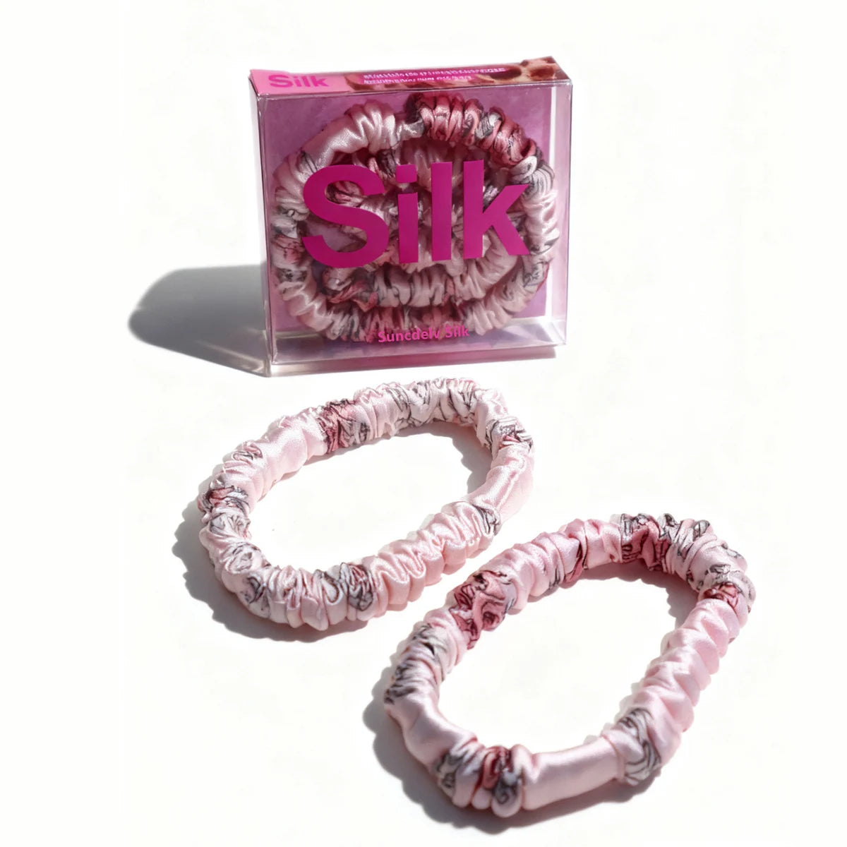 Pink and white patterned hair ties with a 'Silk' branded box on a white background