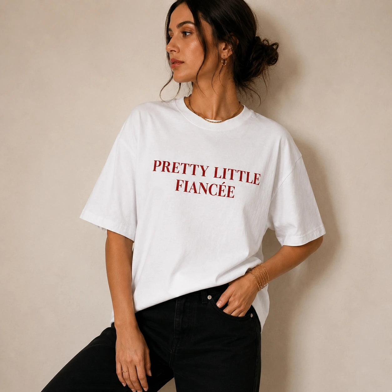 Woman wearing a white t-shirt with 'PRETTY LITTLE FIANCEE' text against a beige background
