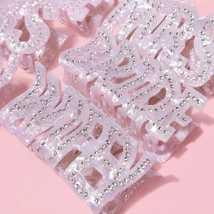White bridal hair clips with rhinestones on a pink background