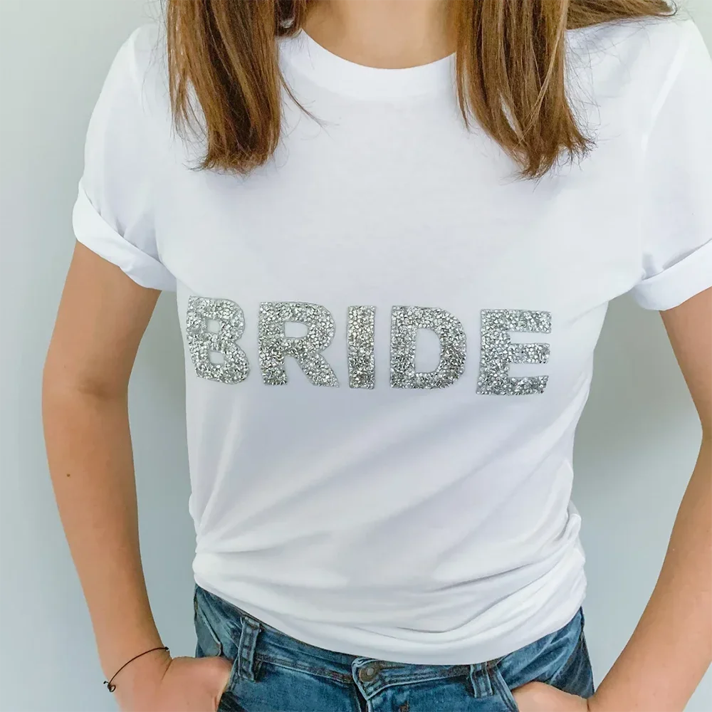 White bride t-shirt with silver rhinestone lettering, styled with jeans for a bridal shower, bachelorette party, or getting ready look from The Hen Planner.