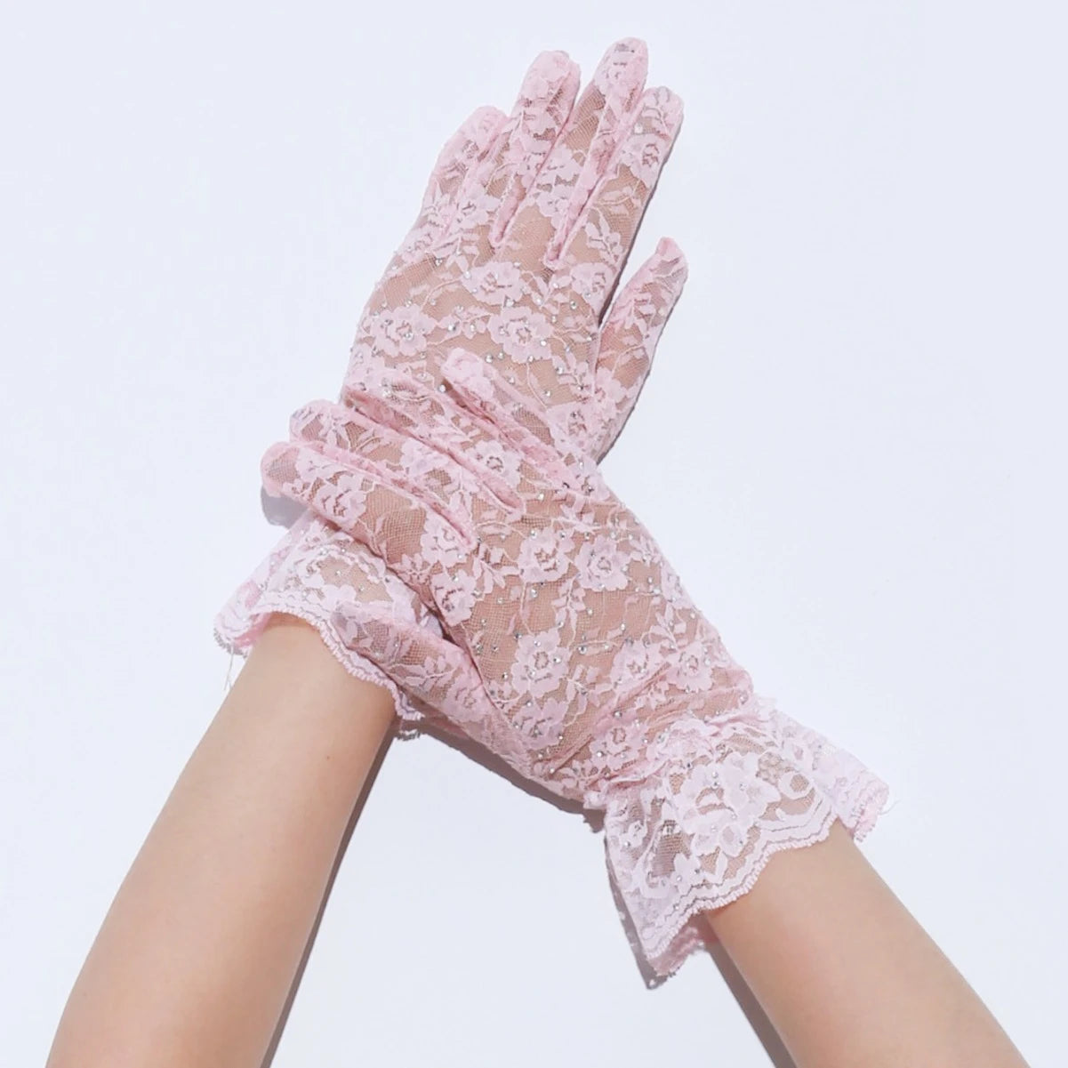 Pink lace gloves being worn on a light purple background