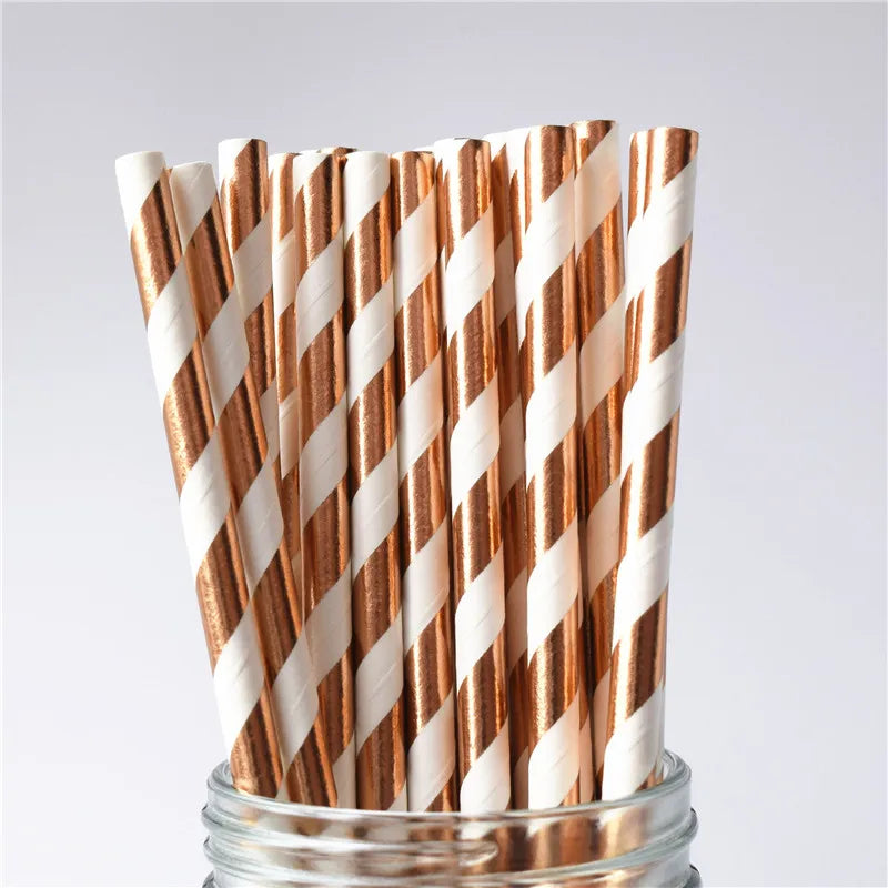 Striped paper straws in a glass container on a light gray background