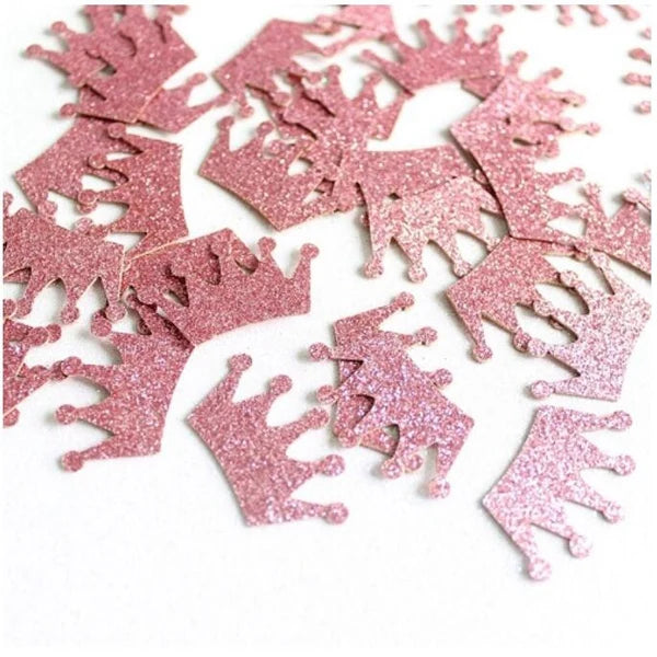 Pink glittery crown-shaped confetti on a white background