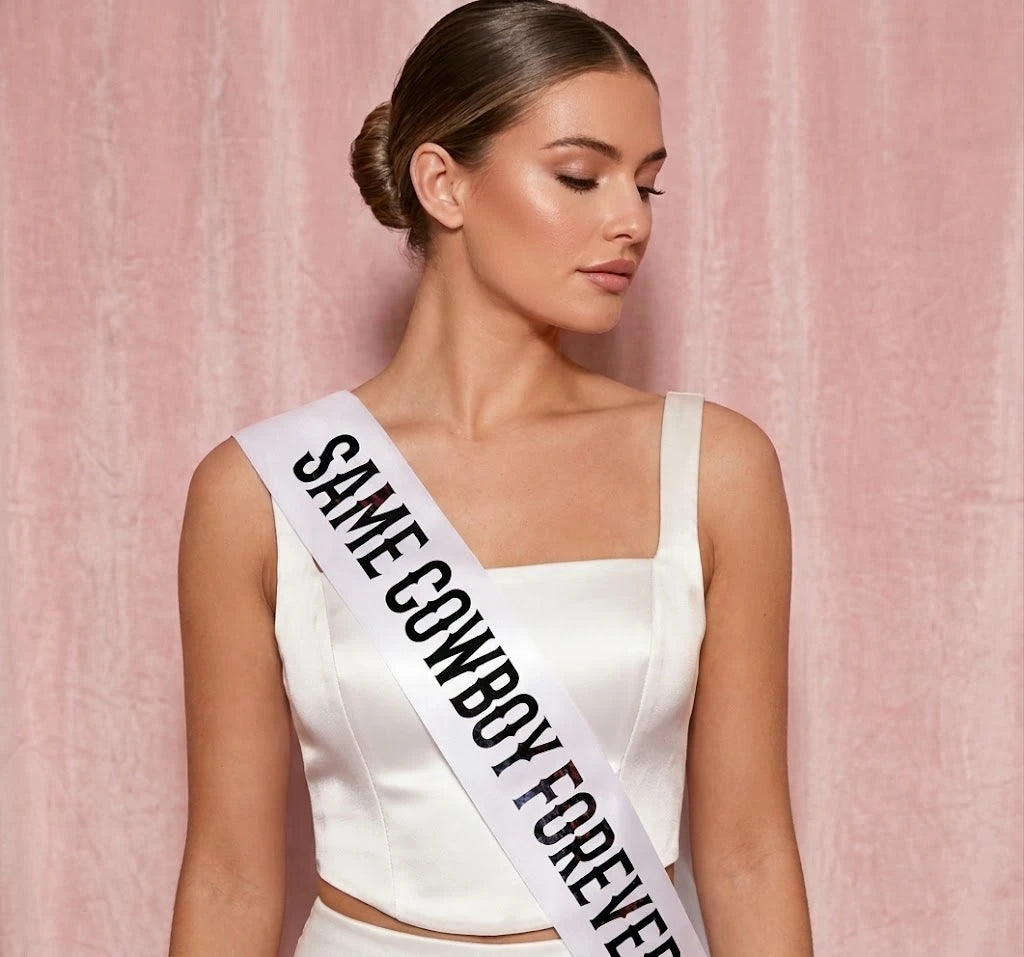 Woman wearing a white dress with a 'Same Cowboy Forever' sash against a pink background