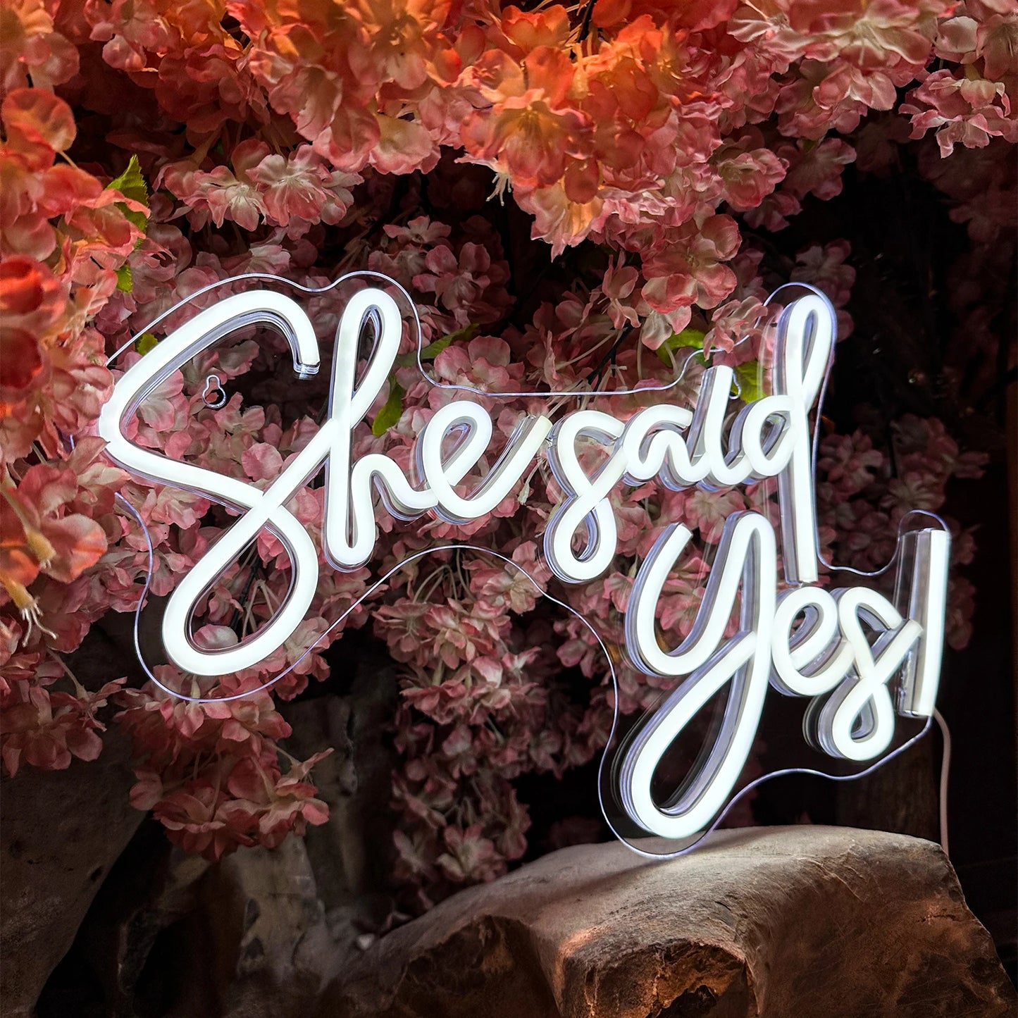 Neon sign with 'She said Yes' surrounded by pink flowers