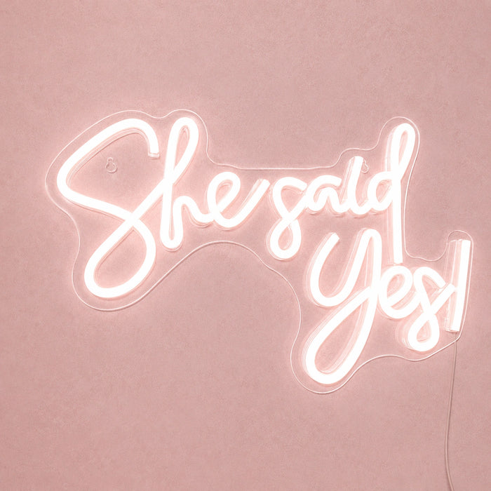Neon sign with 'She said yes!' text on a pink background