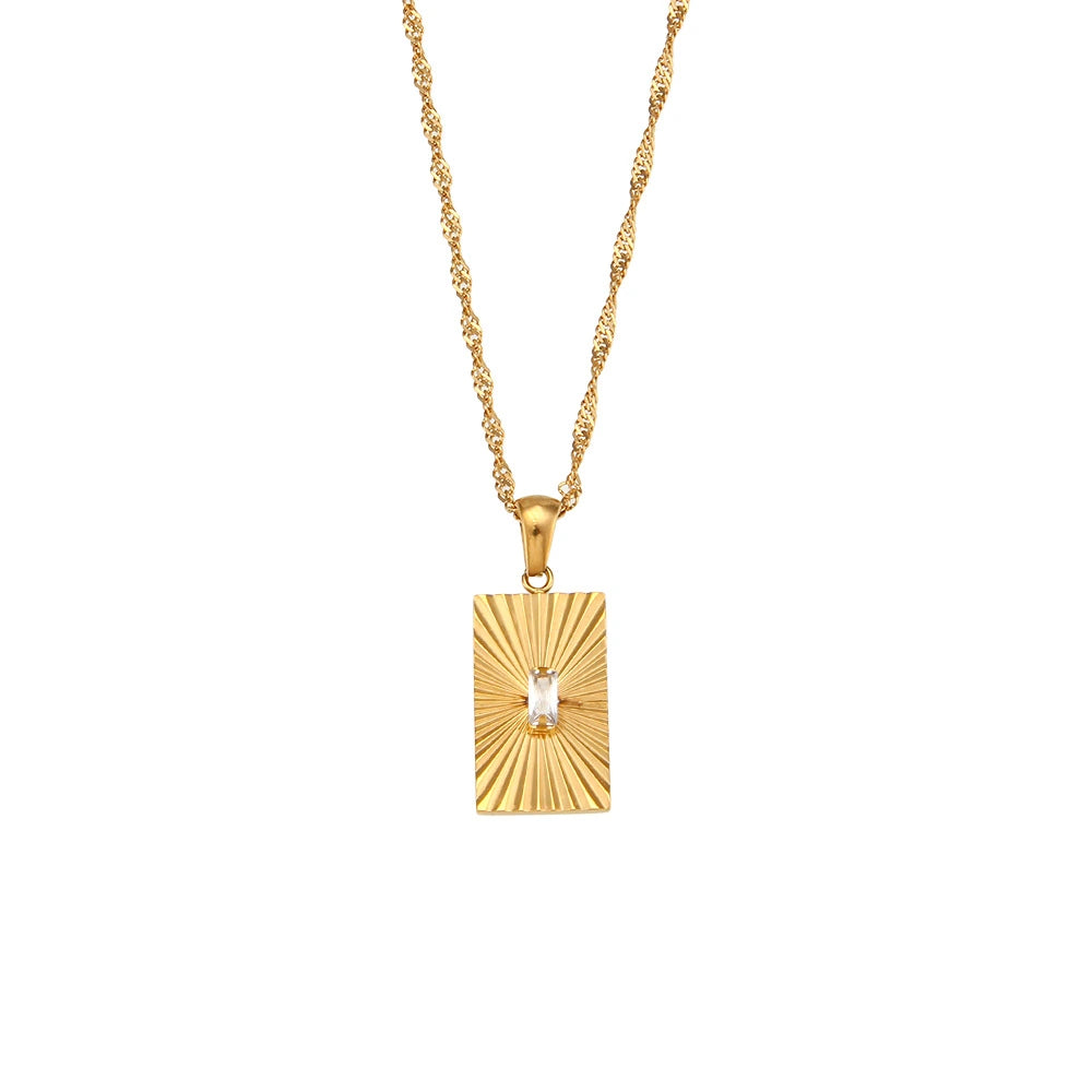 A gold rectangular pendant necklace with a sunburst radial pattern and a small clear central stone, suspended from a gold chain on a plain white background.