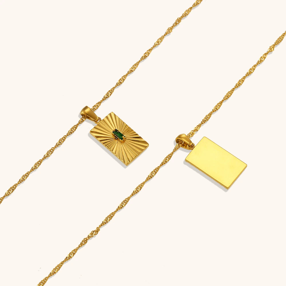 Gold necklace with two pendants on a white background.