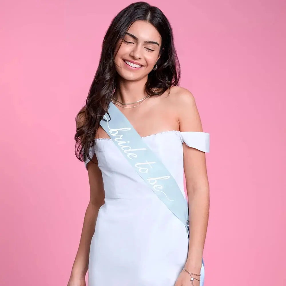 Woman wearing a 'bride to be' sash on a pink background