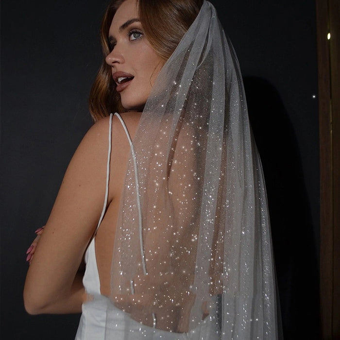 Woman wearing a sparkly veil against a dark background