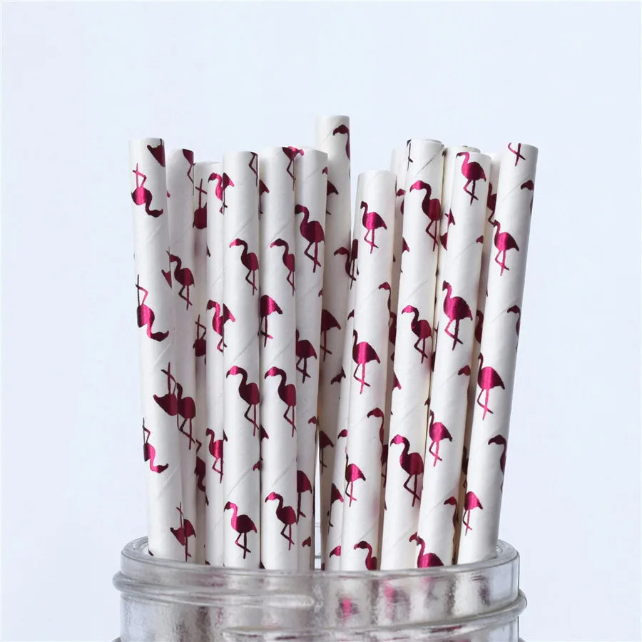 White paper straws with pink flamingo pattern in a glass jar on a light blue background