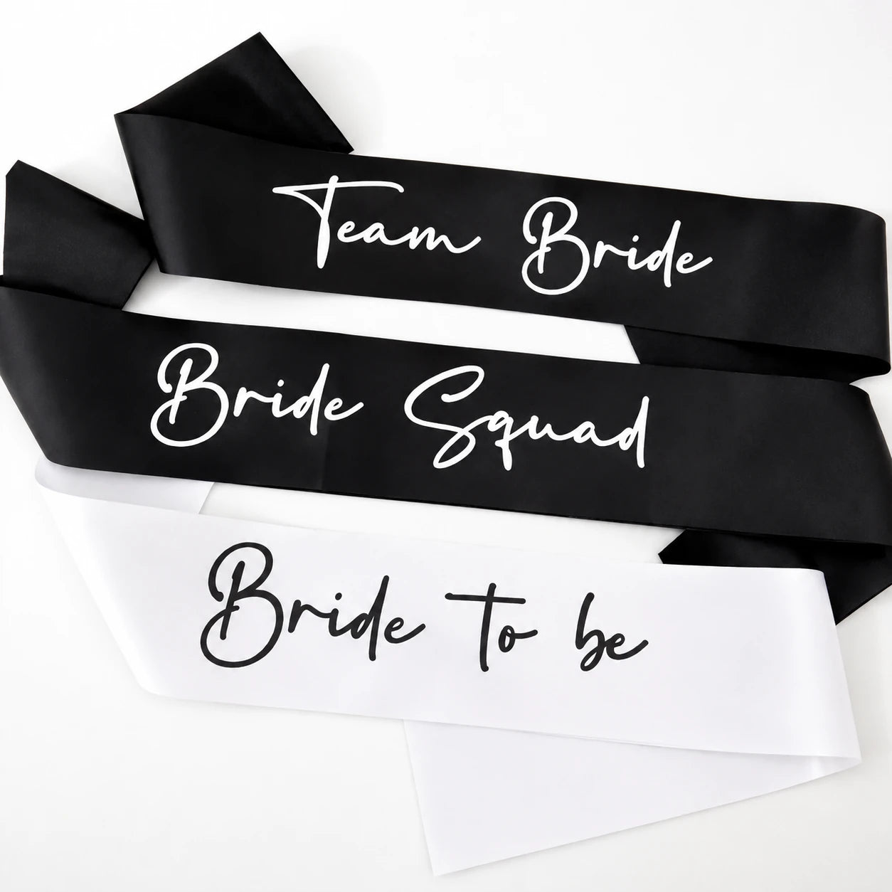 Black satin sashes with white text for a bride and her squad on a white background