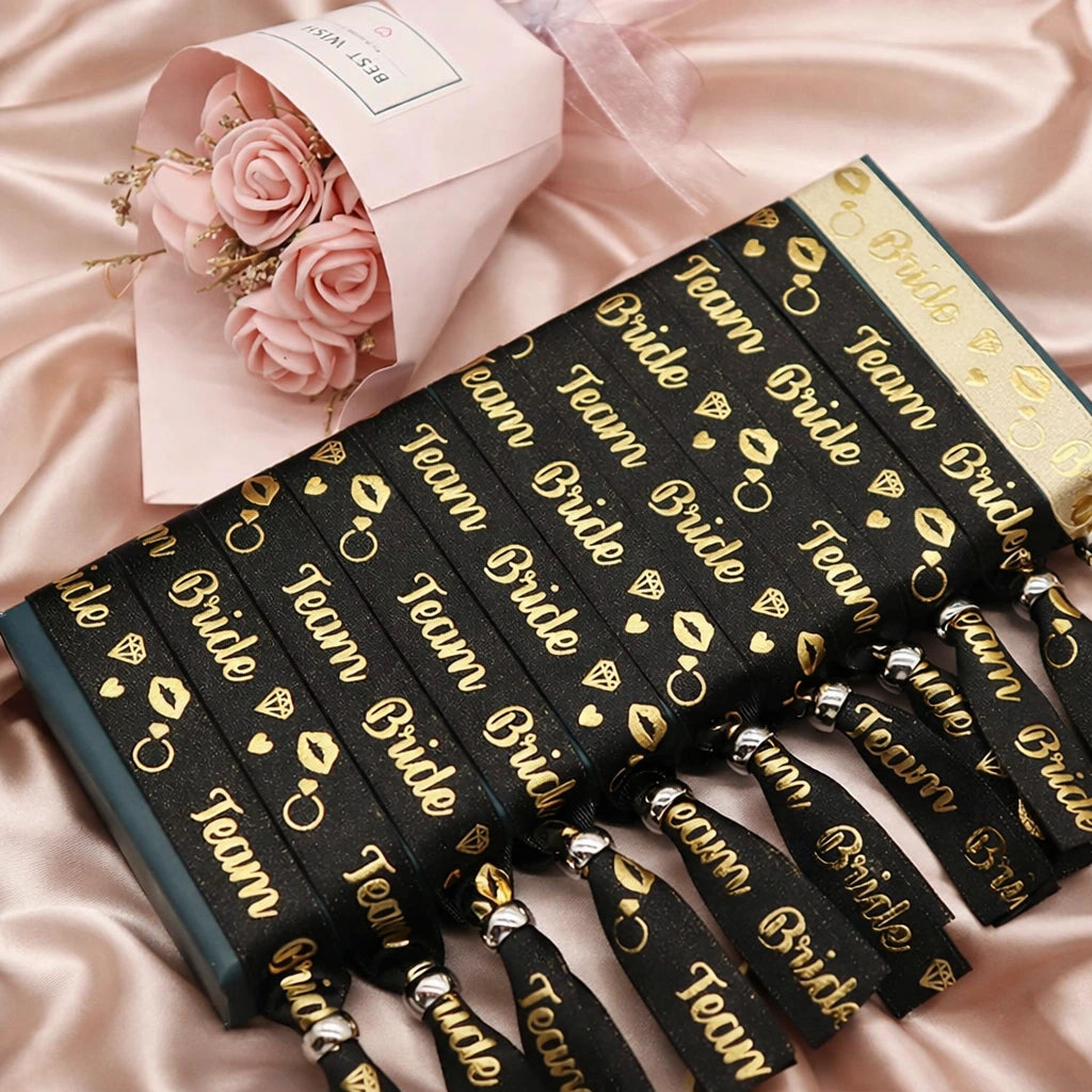 Black hair ties with 'Team Bride' text on a pink satin background