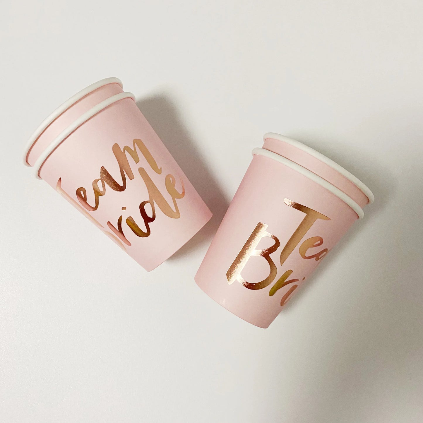 Two pink cups with gold text on a light gray background
