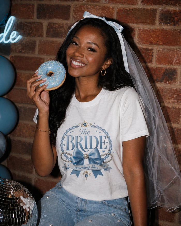 Woman wearing a white 'The Bride something blue' graphic t-shirt with blue veil and blue donut