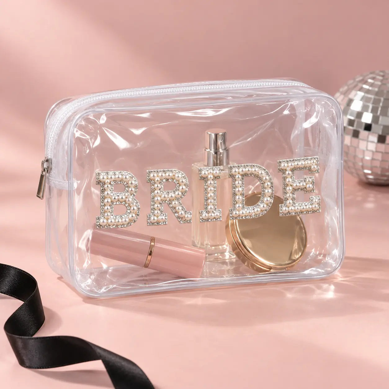 A clear plastic zippered cosmetic bag with the word 'BRIDE' spelled out in rhinestone-embellished letters on the front.