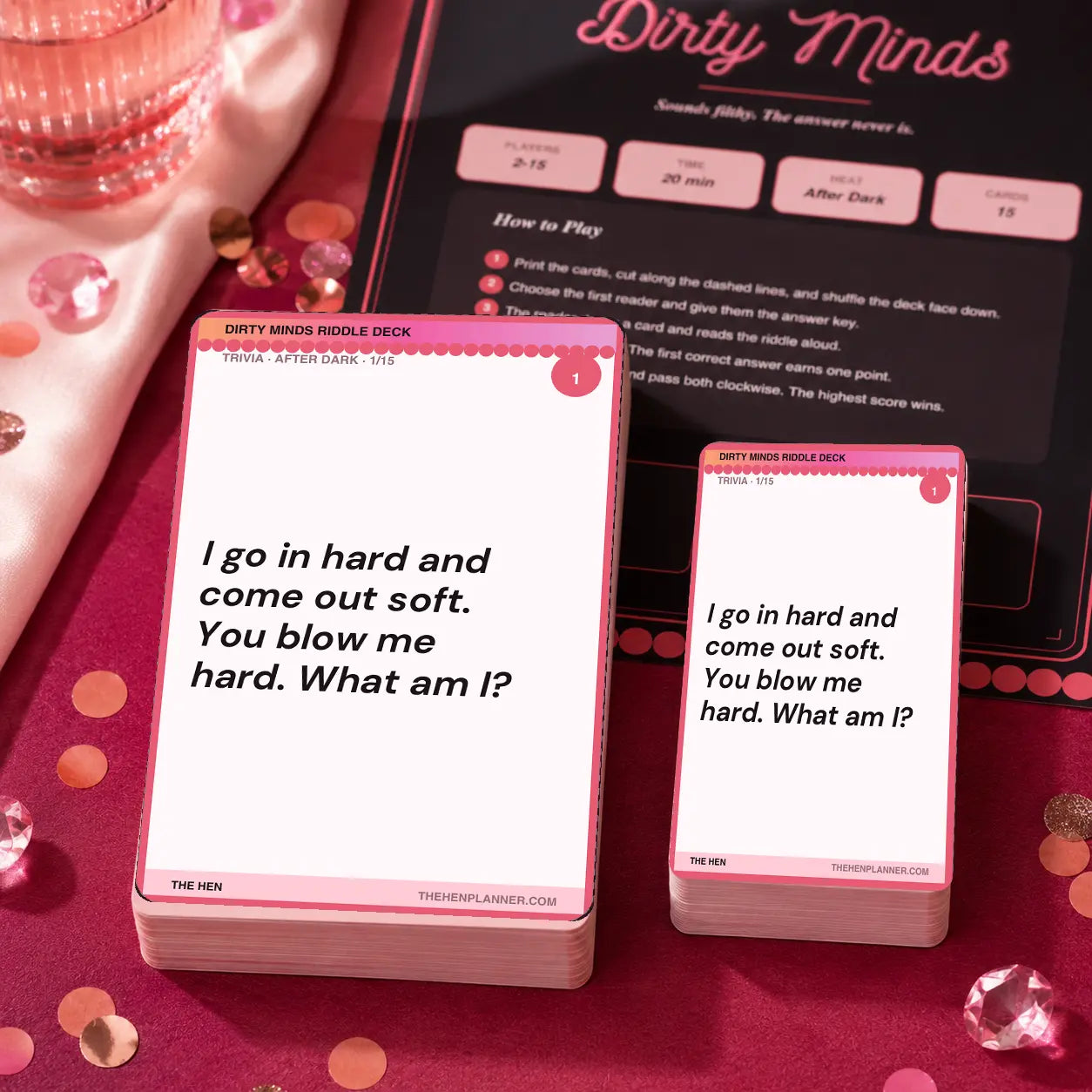 A boxed card deck and a smaller matching card in front of a printed instruction card on a pink tabletop.