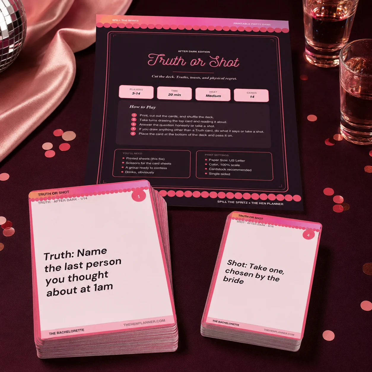 Truth or Shot card game set displayed on a dark tablecloth with pink satin fabric, drink glasses, and confetti. 