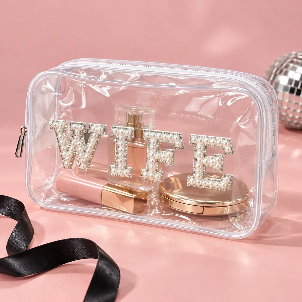 A clear plastic cosmetic pouch with a zipper closure, decorated with large rhinestone-embellished letters spelling 'WIFE'.