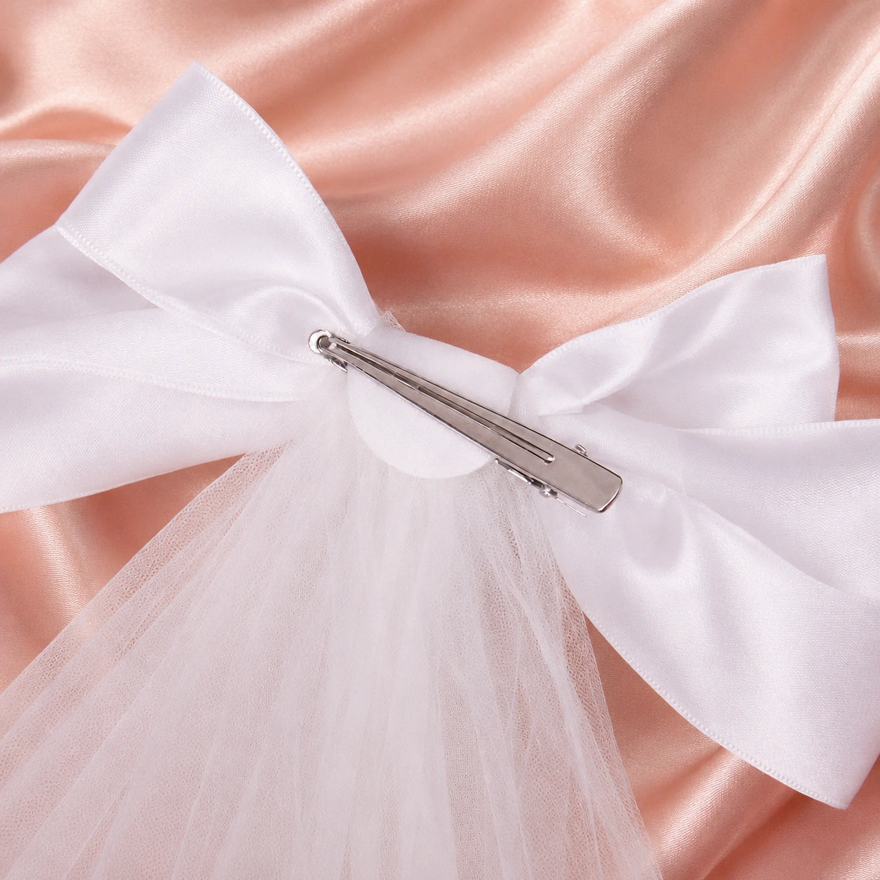 White bow and veil on a pink fabric background