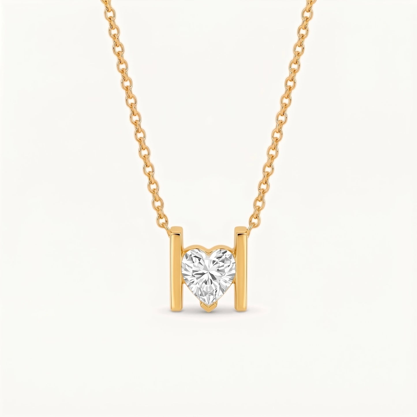 A delicate gold chain necklace featuring a heart-shaped clear gemstone pendant suspended between two vertical gold bars, set against a clean off-white background.