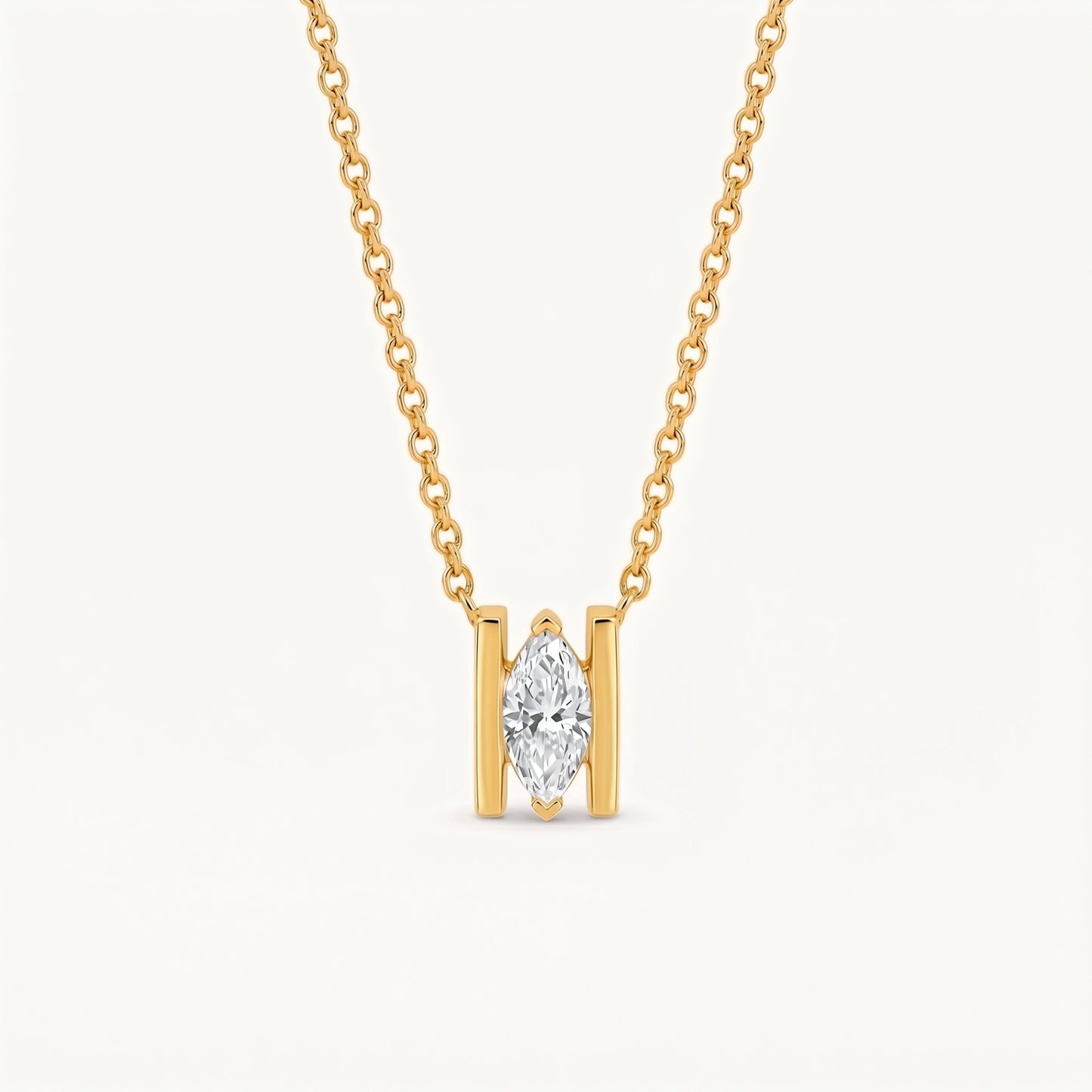 A gold necklace with a single marquise-cut diamond pendant in a gold setting, suspended from a delicate gold chain against a light off-white background.