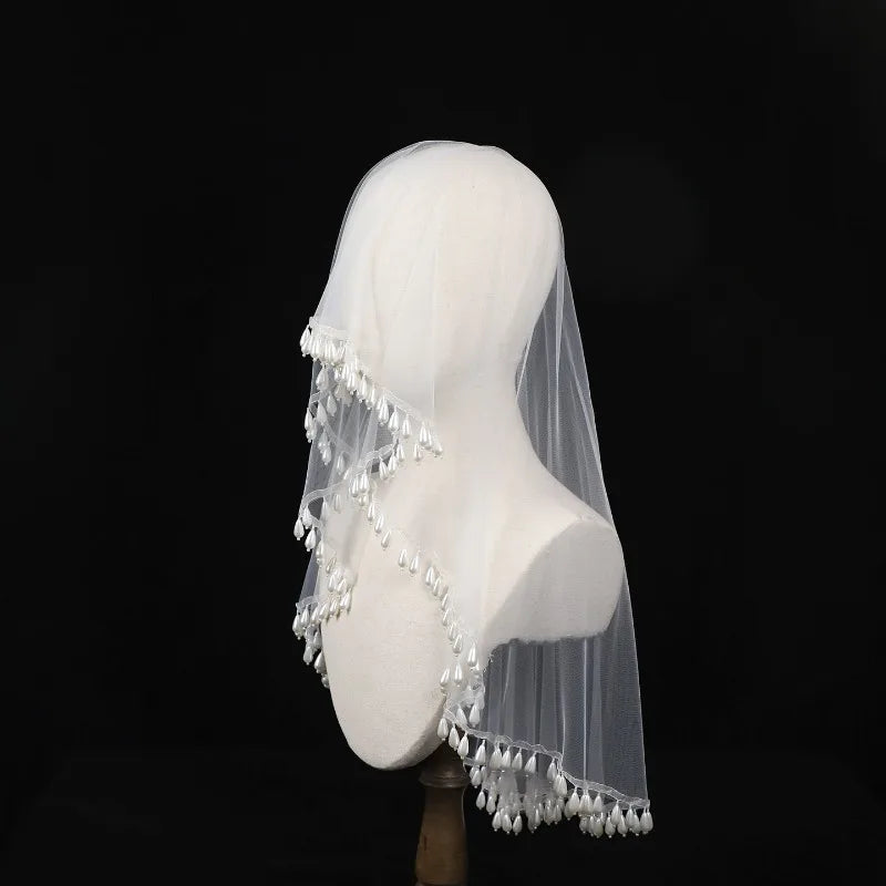 White veil with tassels on a mannequin head against a black background