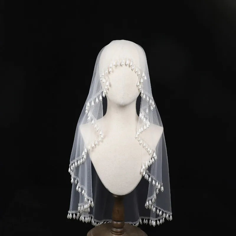 White veil with pearl embellishments on a mannequin head against a black background