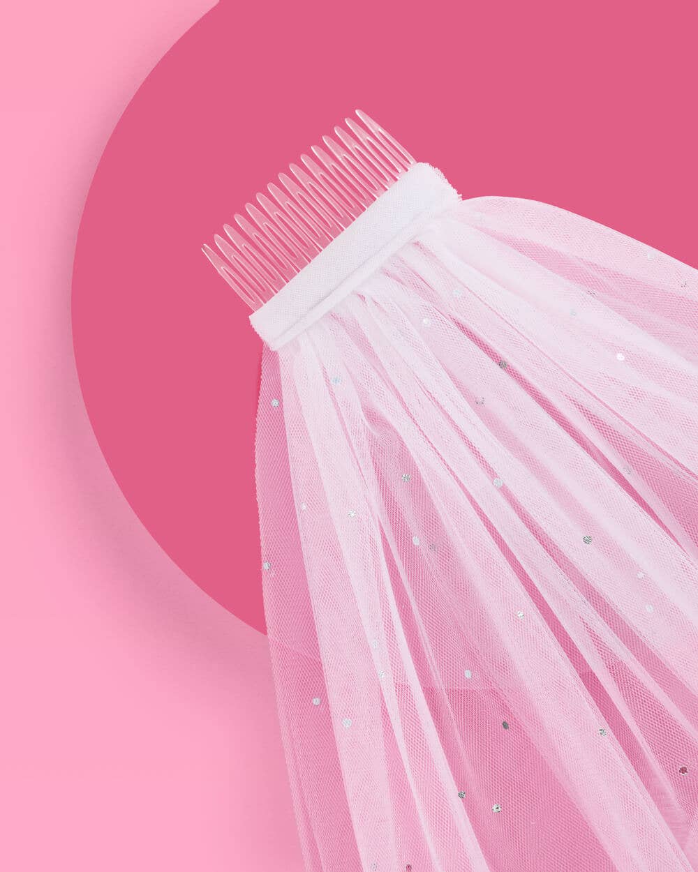 Close-up of a white veil with a comb on a pink background
